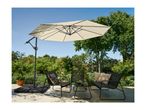 Patio umbrella, two chairs, and a small table on a patio with lush greenery.