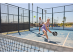 Jogadores de padel numa quadra azul com raquetes e bola.