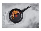 A black frying pan with a cooked chicken leg and vegetables on a grey surface.
