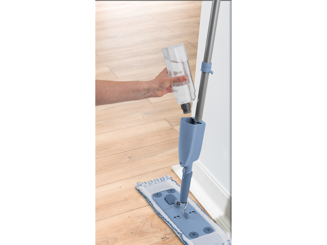 Punjenje sprej mopa bocom tekućine za čišćenje na drvenom podu.