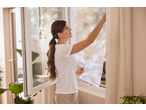 Femeie instalând o plasă anti-insecte LIVARNO la o fereastră deschisă.