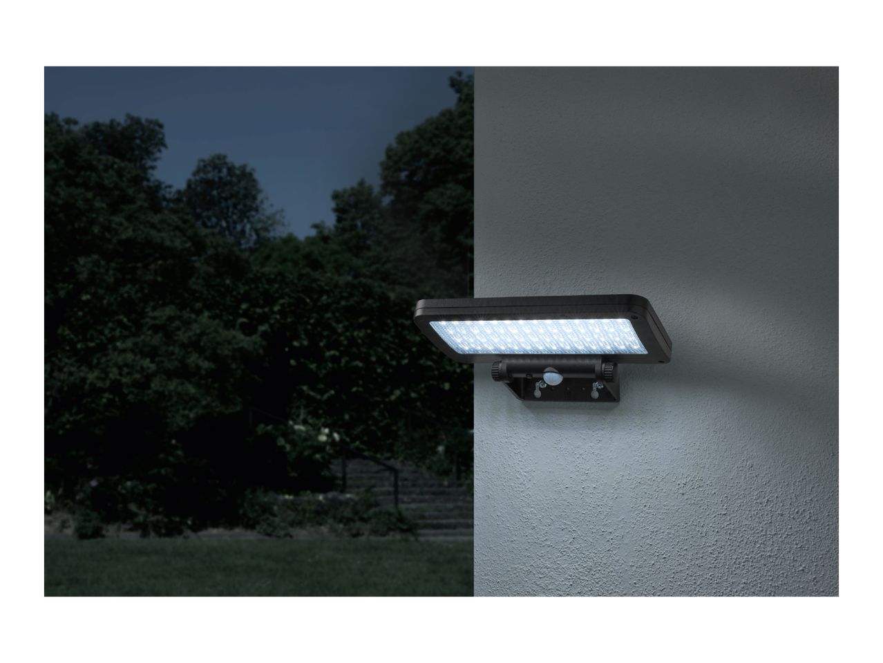 A solar-powered LED security light mounted on a wall at night, illuminating the area.