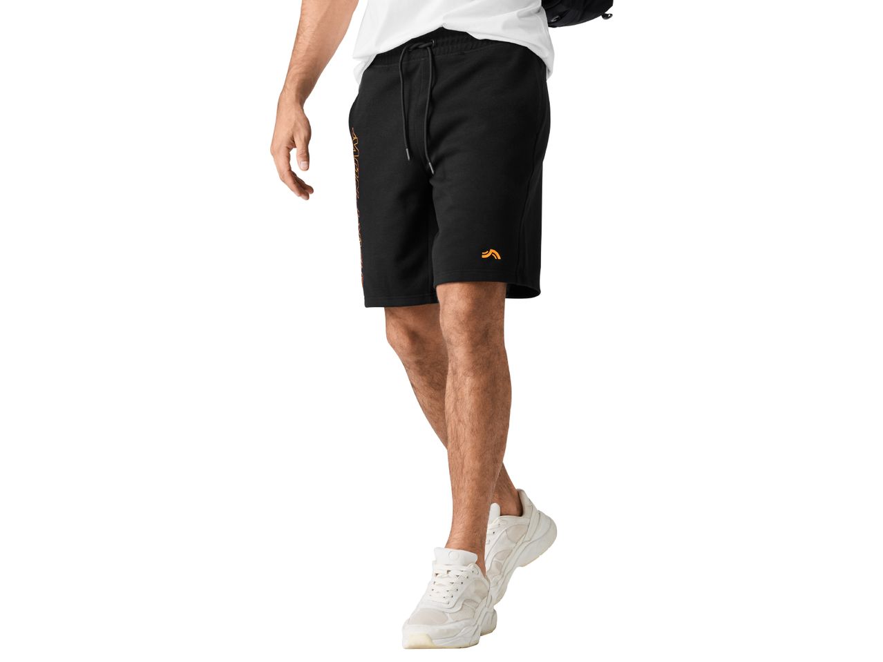A man wearing black shorts with an orange logo and white sneakers.
