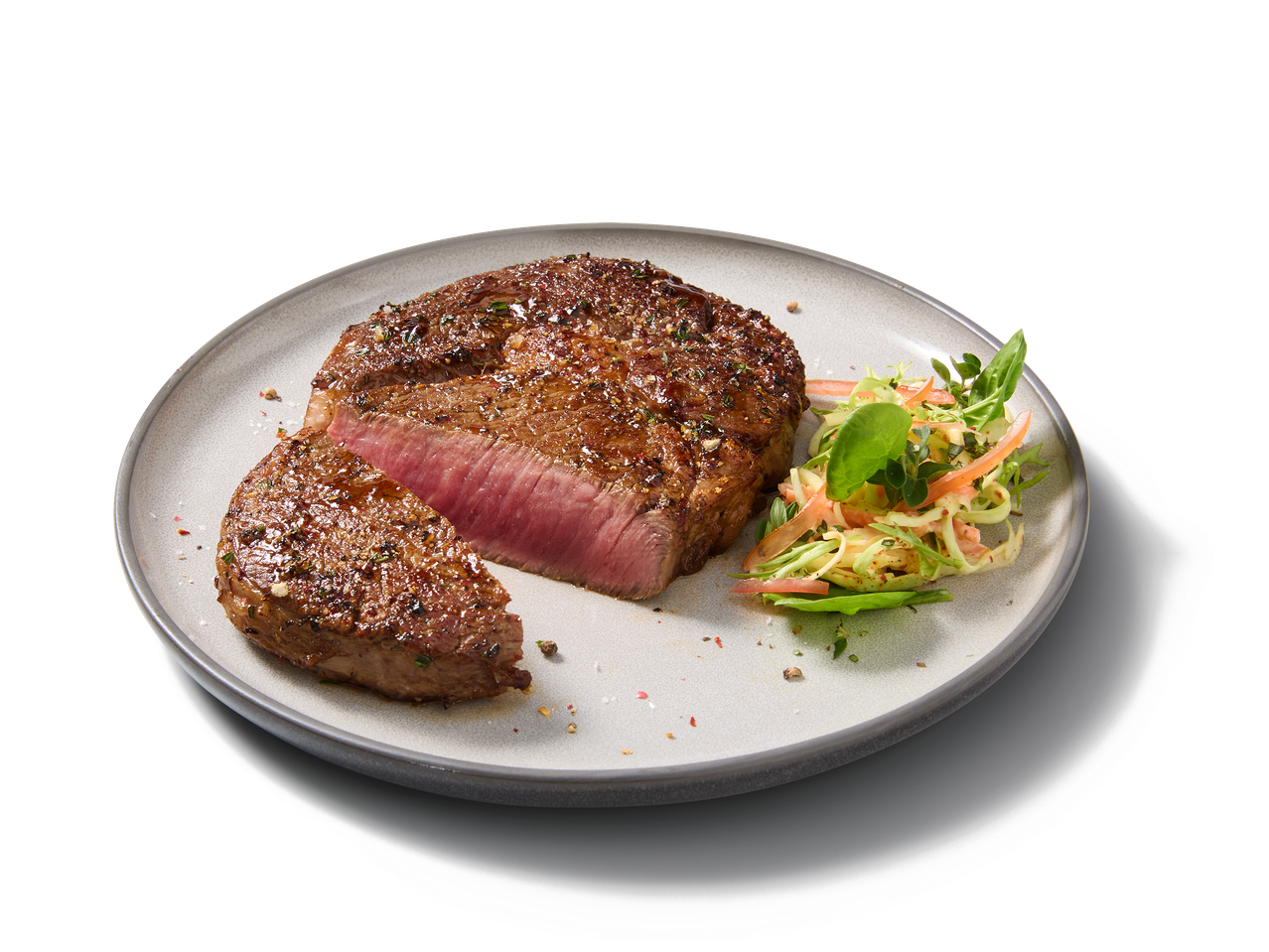Steak de bœuf grillé avec une tranche coupée, accompagné d'une salade fraîche.