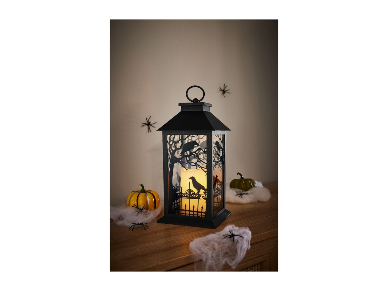 Halloween lantern with a glowing candle, pumpkins, fake cobwebs and spiders