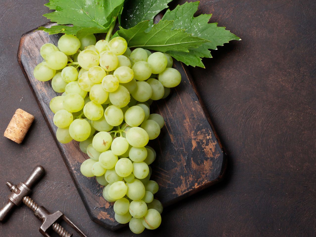 Grozđe na drvenoj dasci sa čepom i otvaračem za vino.
