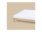 A wooden bed frame with a white mattress on a beige background.