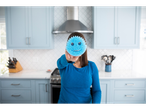 Een vrouw houdt een blauwe Scrub Daddy spons met een lachend gezicht vast in een keuken.