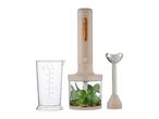 Beige immersion blender with a chopper attachment containing herbs, a measuring cup, and a blending shaft.