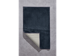 Een donkerblauwe badmat op een grijze vloer.