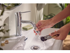 Acessório de torneira LIVARNO em uso, limpando pincéis de maquiagem na pia.