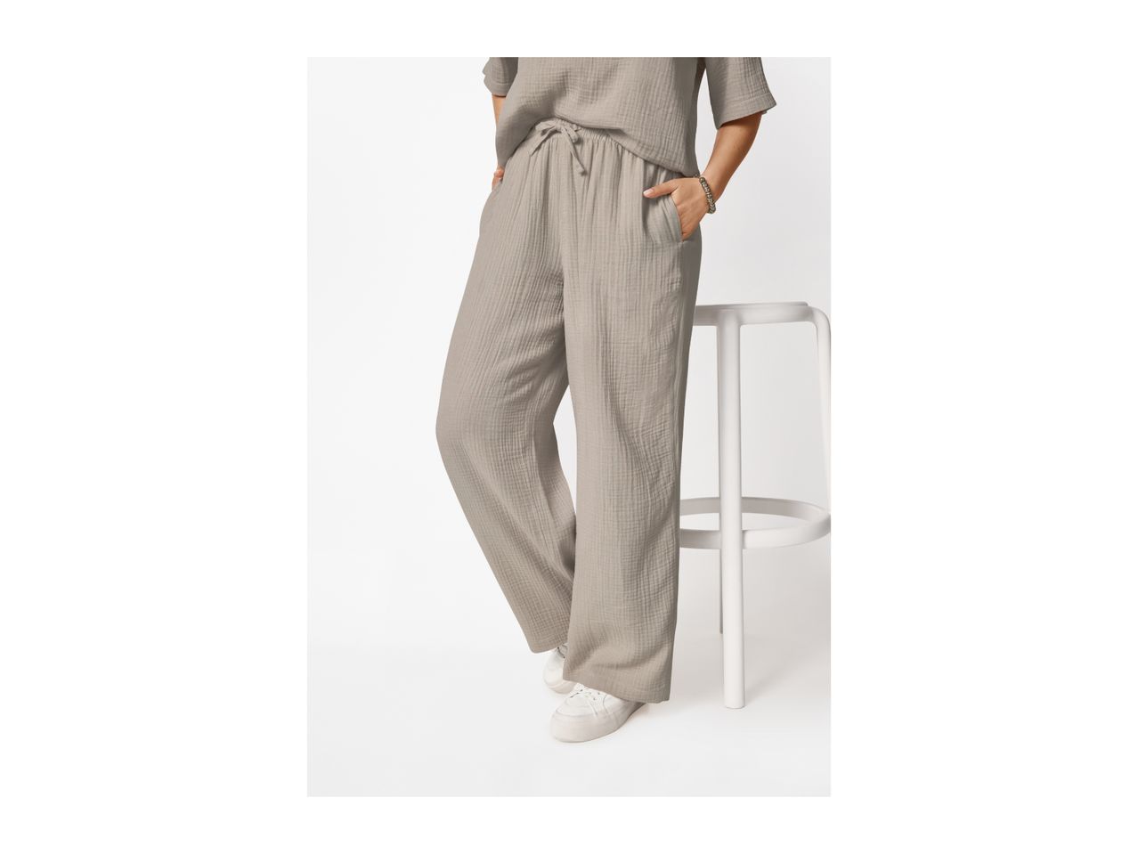 Woman wearing a light grey crinkled short-sleeved top and matching wide-leg trousers.