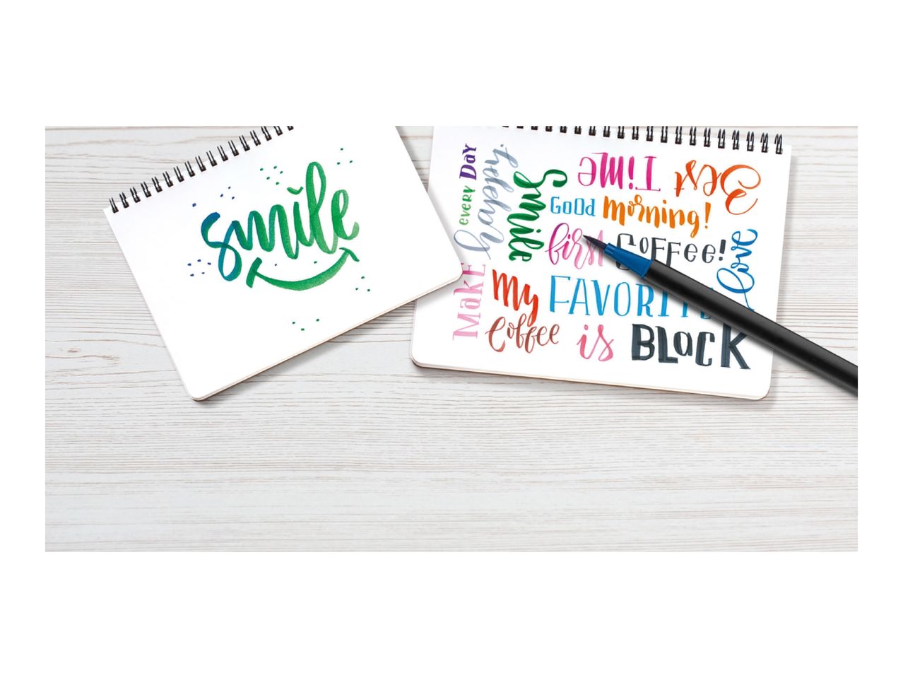 Two notebooks with colorful calligraphy, one saying 'Smile' and the other with various phrases.