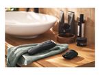 Electric beard trimmer and comb attachment on a towel next to a sink and toiletries.