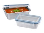 Two stainless steel food containers with clear lids, one filled with tomato soup.