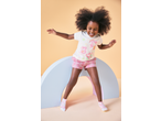 Smiling girl in pink Peppa Pig jersey shorts and matching top, standing over a rainbow prop.