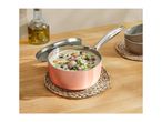 Pink saucepan with creamy mushroom soup, oil bottle, and bowls on a wooden table.