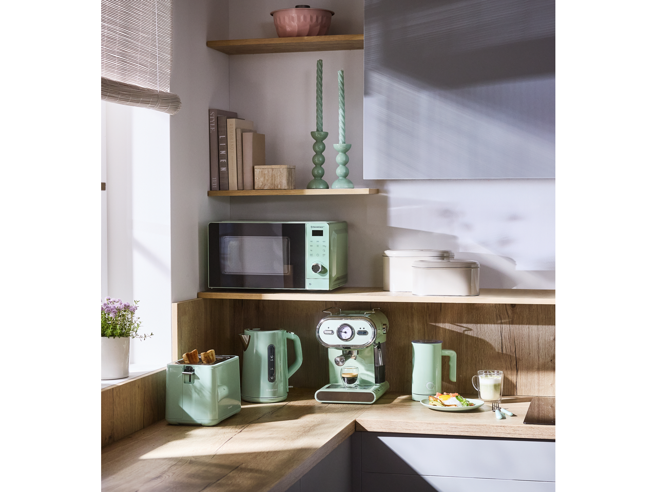 Bancada de cozinha com eletrodomésticos verde menta: micro-ondas, torradeira, chaleira e máquina de café.