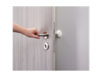 A hand reaches for a modern door handle on a light gray wood door.