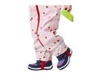 Child in pink heart-patterned waterproof overalls and navy shoes, holding a green toy.