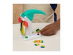 Child's hand holding a colorful playdough creation next to a playdough machine with extruded strands.