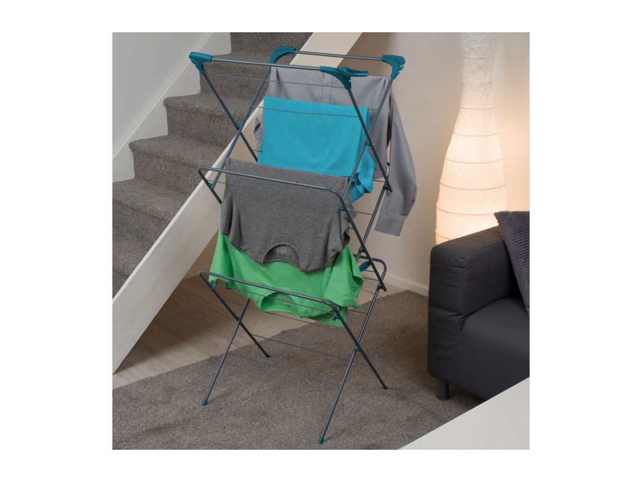 Clothes drying rack with various garments, including shirts and underwear, in a living room setting.