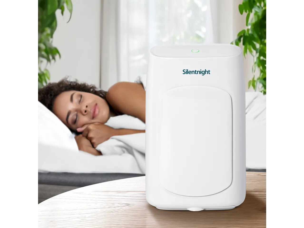 Silentnight Airmax 600 Dehumidifier on a table with a sleeping woman in the background.