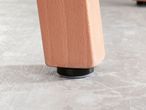 Close-up of a wooden furniture leg with a black and grey floor protector.