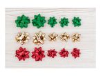 Rows of green, gold, and red gift bows in various sizes on a light wooden background.