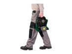 Person in work trousers carrying a portable fan with a battery pack.