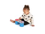 Toddler playing with a blue and red toy bongo drum with animal faces.