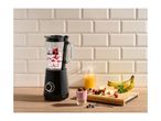 Blender with fruit and yogurt, fresh fruit, and juice on a wooden counter.