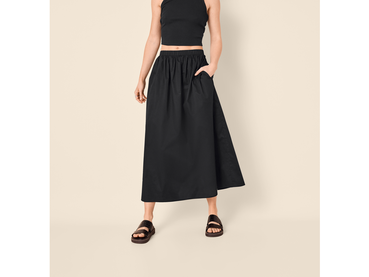 Saia midi preta Esmara, combinada com um top preto e sandálias.