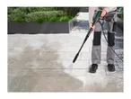 Person cleaning patio with a pressure washer, showing before and after cleaning.