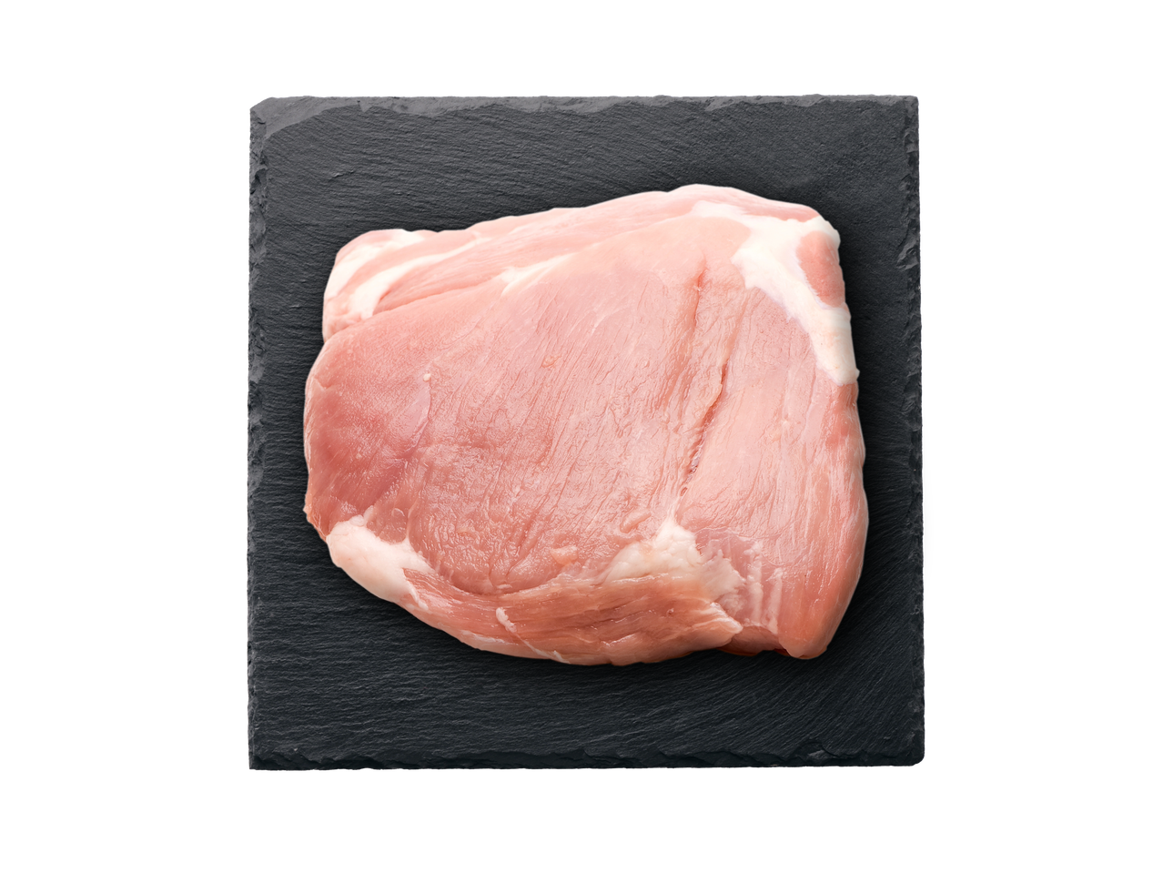 Neapstrādāta cūkgaļas kotlete uz tumši pelēka šīfera plāksnes.