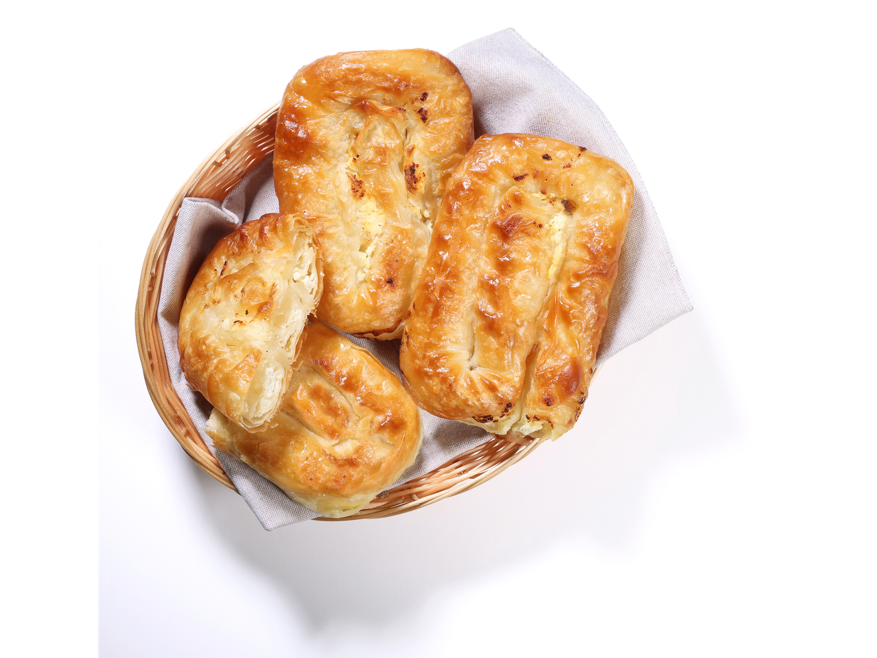 Štirje zlato-rjavi bureki s špinačo in sirom v pleteni košari.