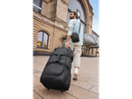 Man pulling a large wheeled duffel bag and carrying a shoulder bag.