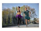 Two people running outdoors, wearing sports tops, leggings, and shorts.