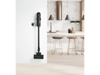 Aspirador vertical sem fios 2 em 1 Silvercrest®, a carregar numa parede branca numa cozinha moderna.