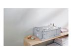 Grey storage crate with bottles and towels on a wooden shelf in a bathroom setting.