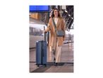 Woman with a blue suitcase and grey shoulder bag walking on a train platform.