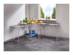 Corner kitchen setup with two folding tables, kitchenware, plants, and bottled water.