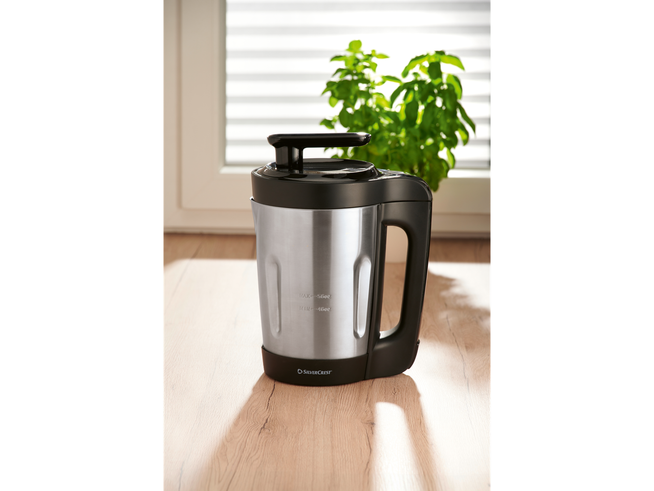 SilverCrest soup maker on a wooden surface with a plant and window in the background.