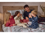 Family in fleece pajamas on a bed, children playing with toy cameras.