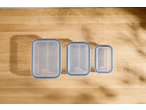 Three rectangular SILVERCREST® Glass Food Storage Containers with blue lids on a wooden surface.