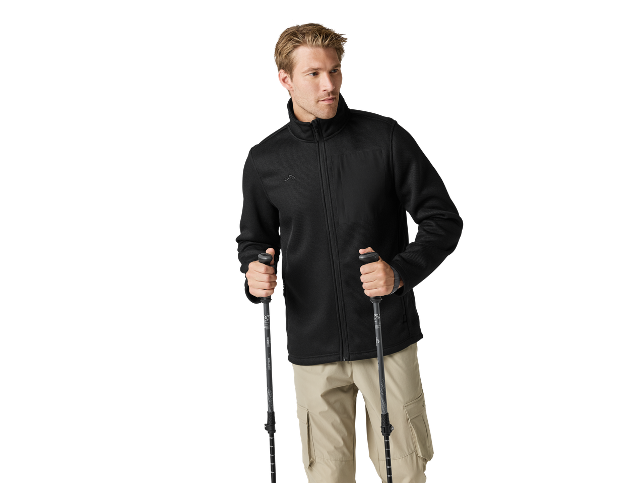 Vyras su juoda fliso striuke ir smėlio spalvos kelnėmis laiko žygio lazdas.