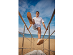 Man in a white seersucker shirt and shorts, stepping down beach stairs.