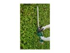 Person trimming a green hedge with a cordless hedge trimmer.