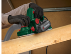 Person planing wood with an electric planer, wearing work gloves.