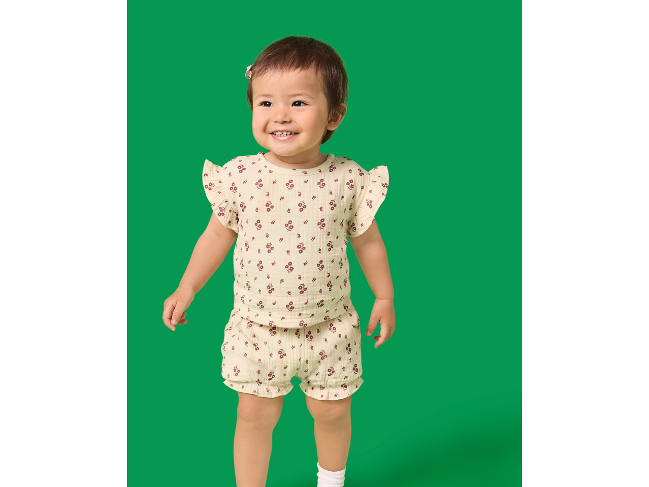 Set de muselină pentru fetițe cu model floral, purtat de un bebeluș zâmbitor.